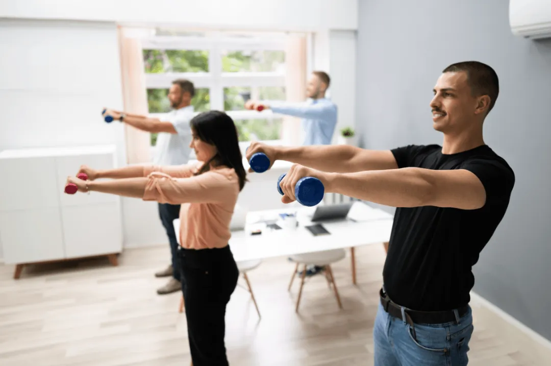 Four office workers doing a light dumbbell workout together in an office space.
